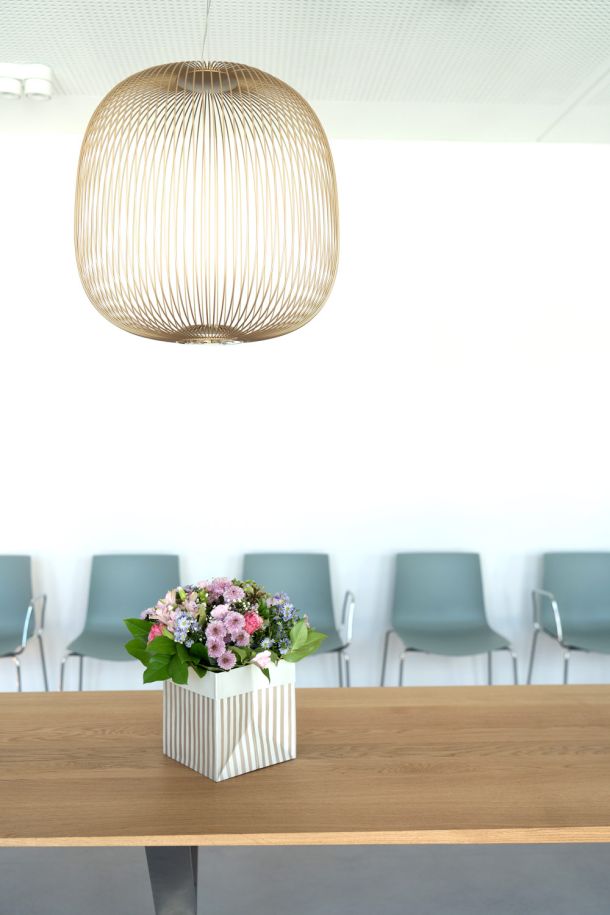 Blumengesteck auf Holztisch im Wartebereich der Herzpraxis Magdeburg – moderne, freundliche Atmosphäre.