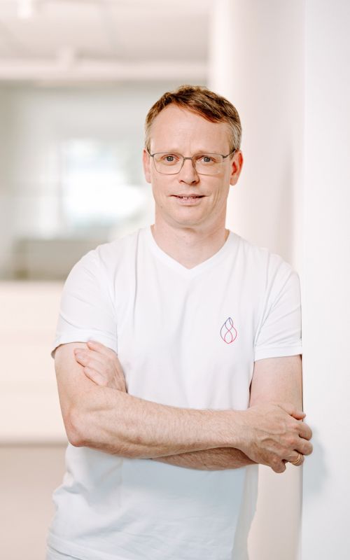 Dr. med. Jan Smid in der Herzpraxis Magdeburg mit verschränkten Armen, freundlich und vertrauensvoll im Praxisumfeld.